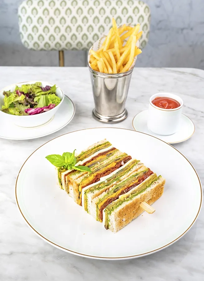 A brown bread club sandwich with a pesto and vegetable filling.