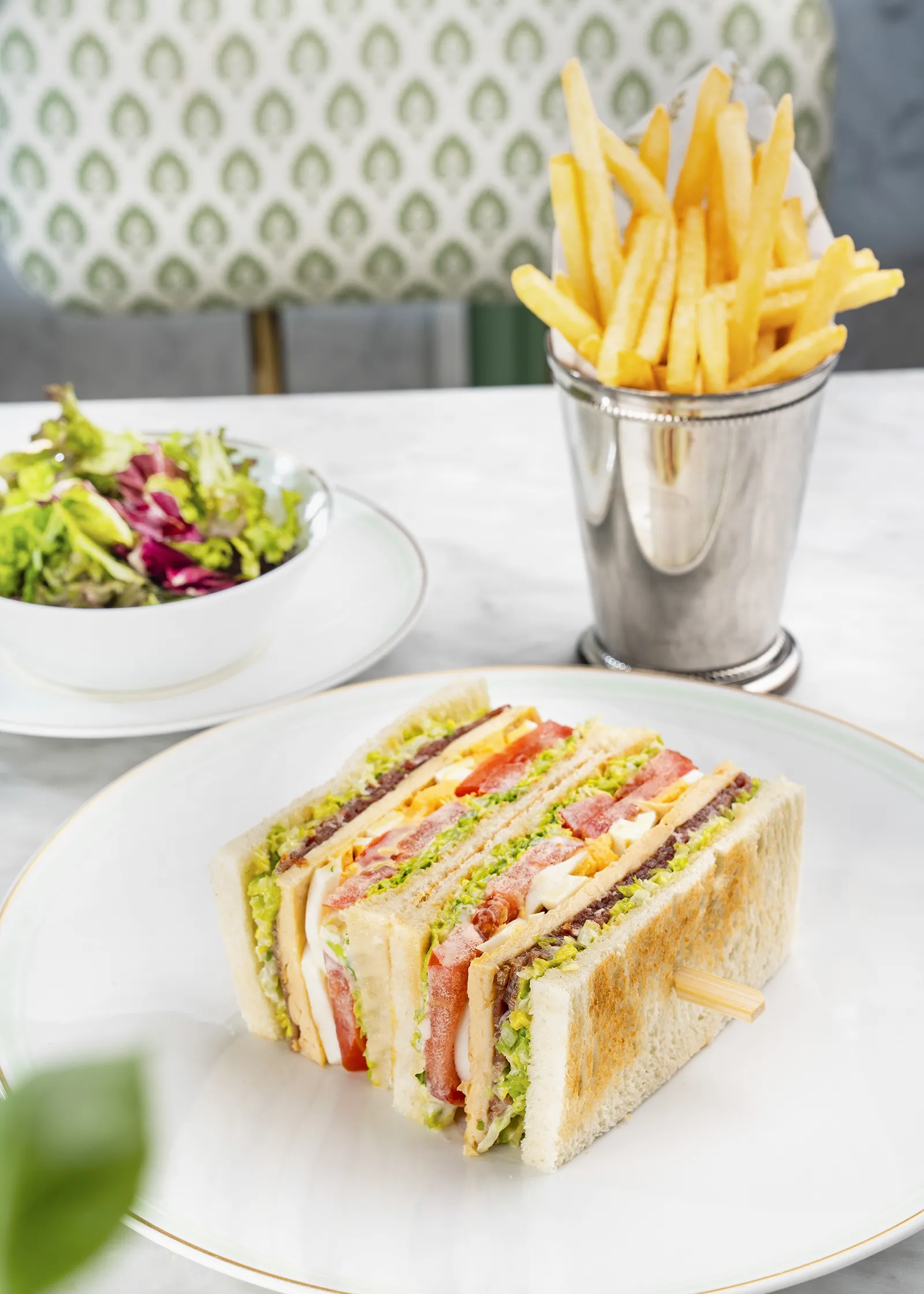 A classic club sandwich with a chicken and bacon filling, served with a salad.