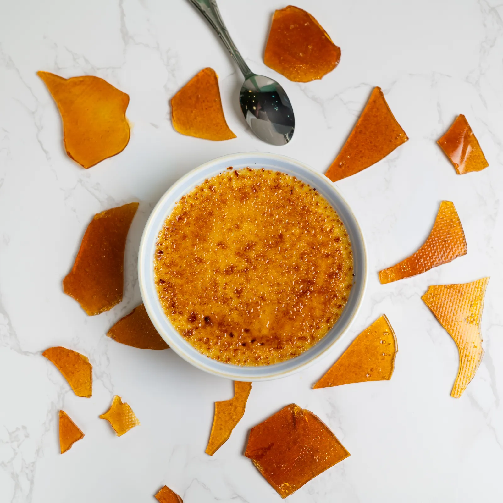 A ramekin of crème brûlée with a cracked caramelized top.