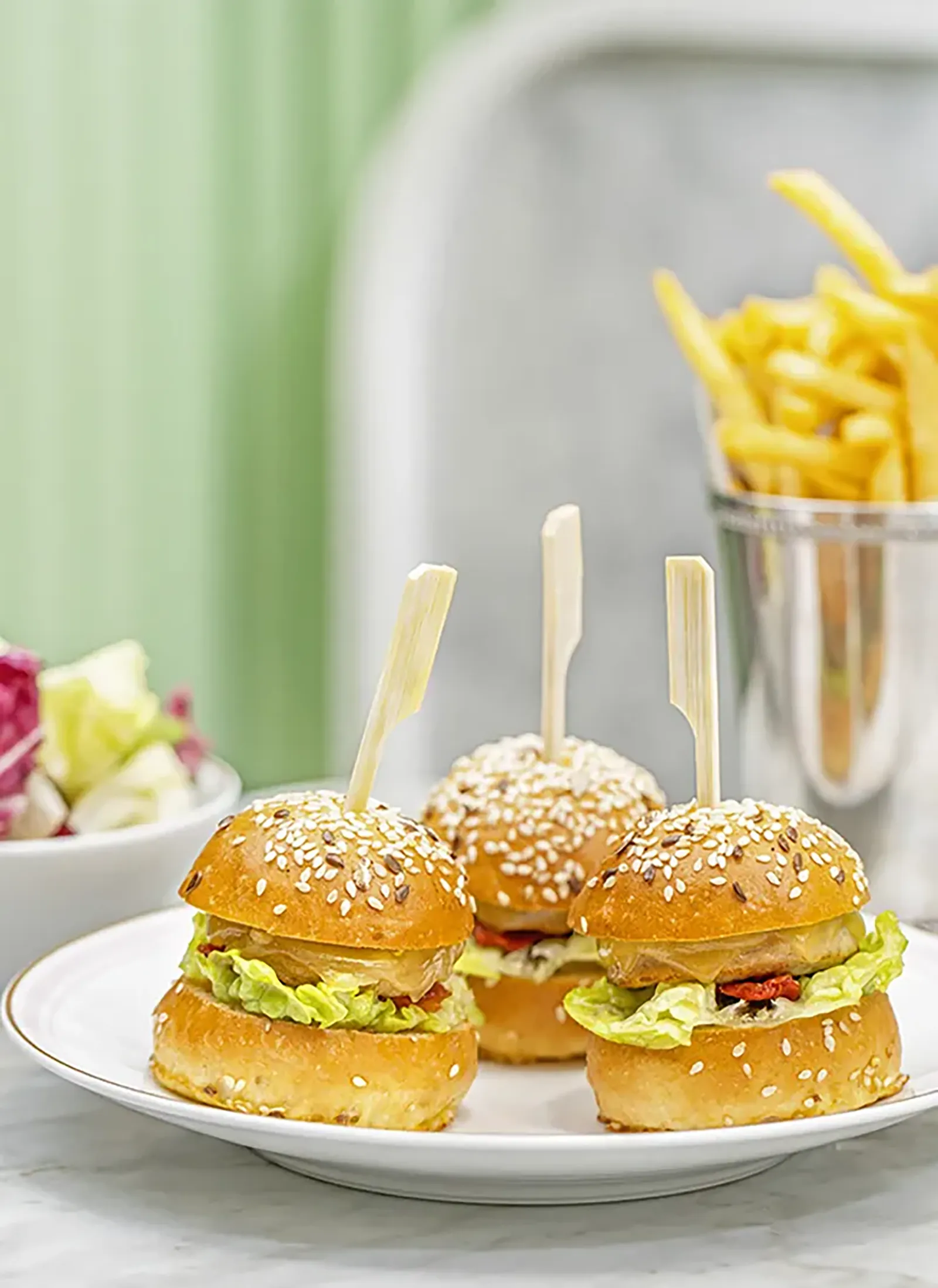 Two small chicken sliders served with potato chips and salad.