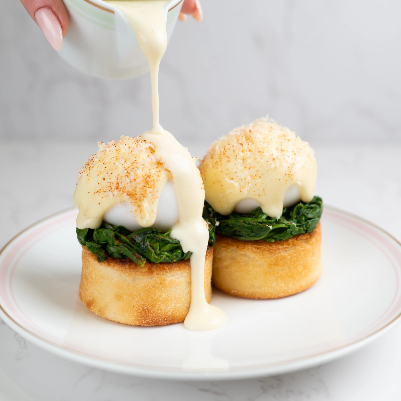 A dish of English muffins topped with sautéed spinach and eggs.