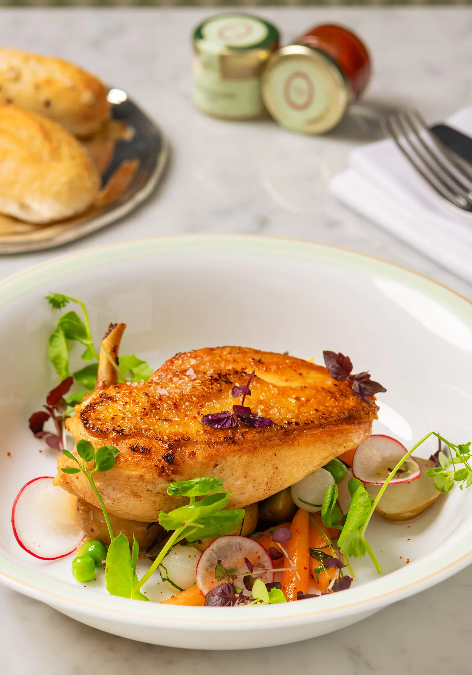 A plate of grilled chicken with baby vegetables.