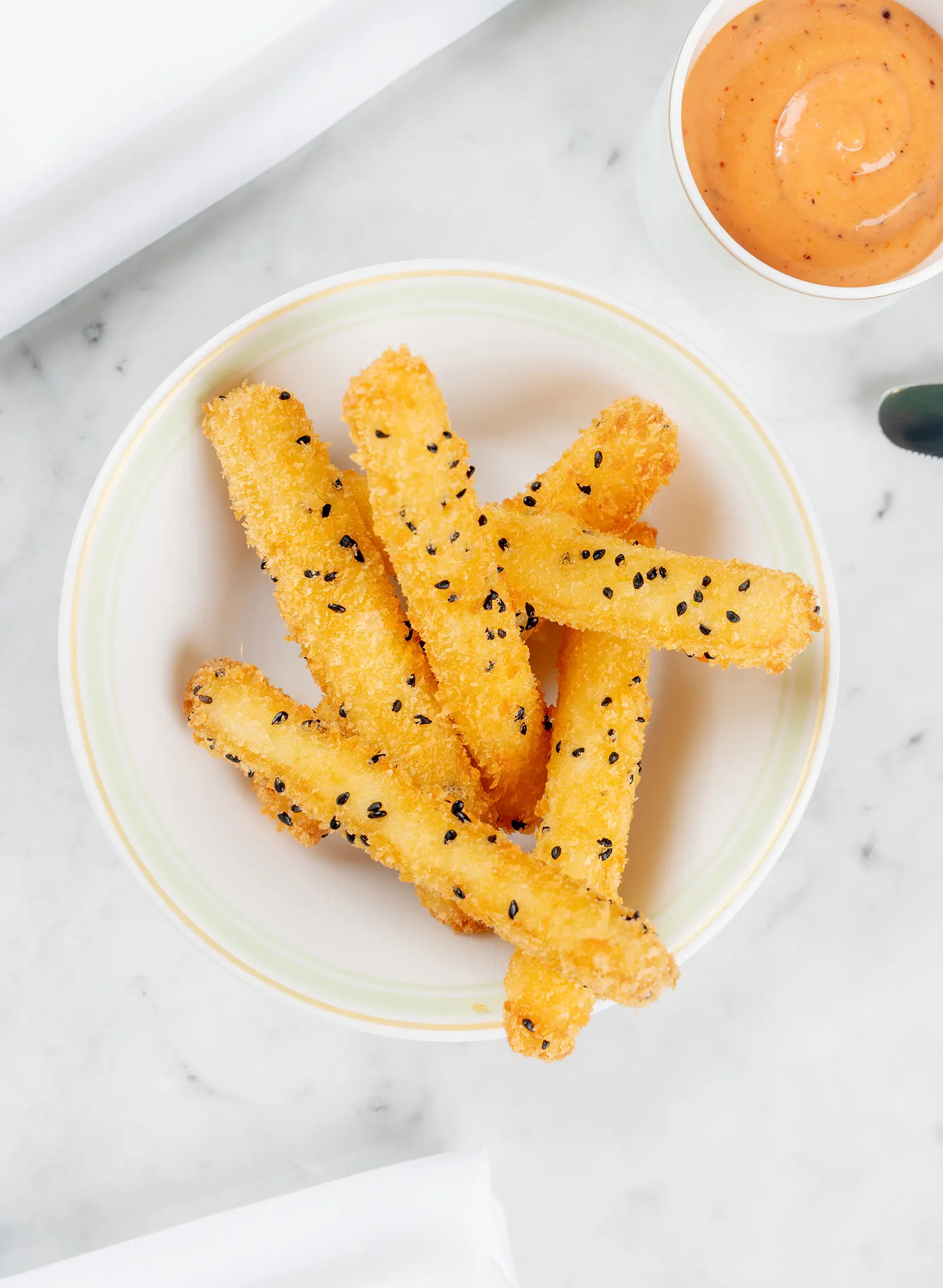 Crispy fried halloumi sticks arranged on a plate with dipping sauces.