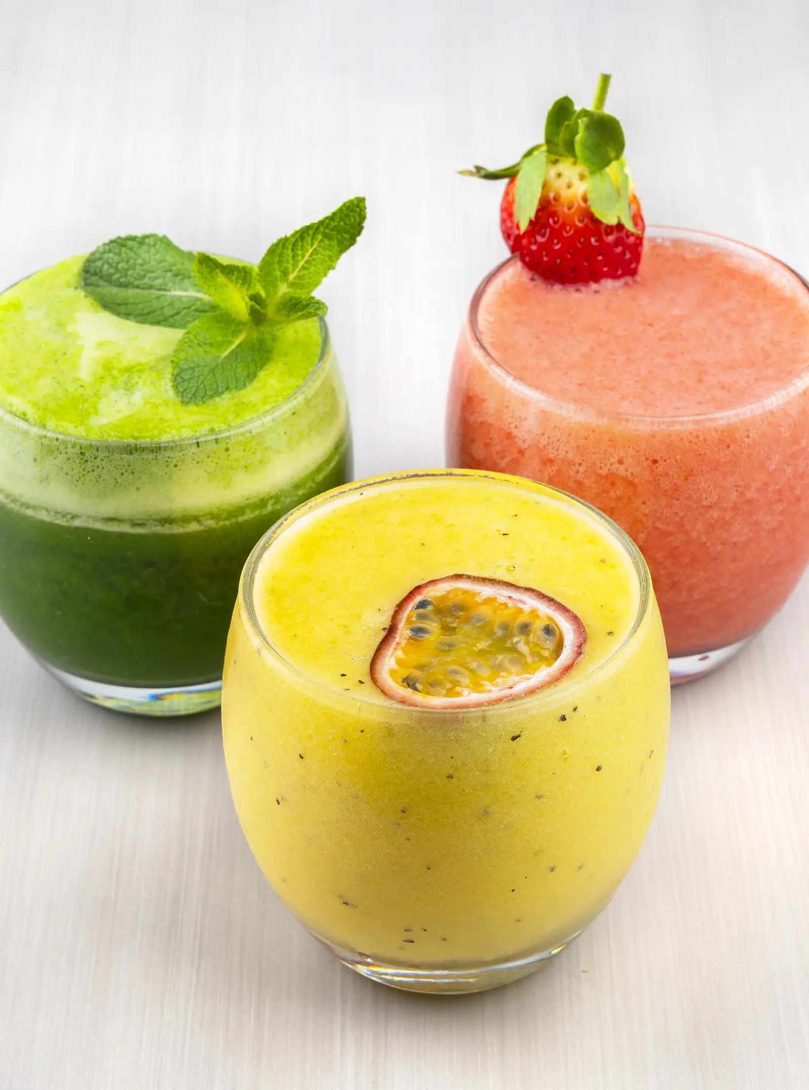 A glass of yellow juice garnished with fruit.