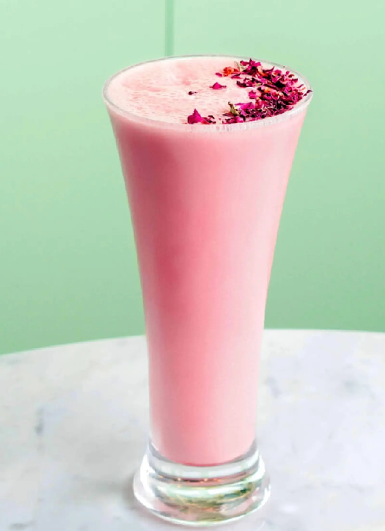 A pink drink with lychees and a rose petal garnish.