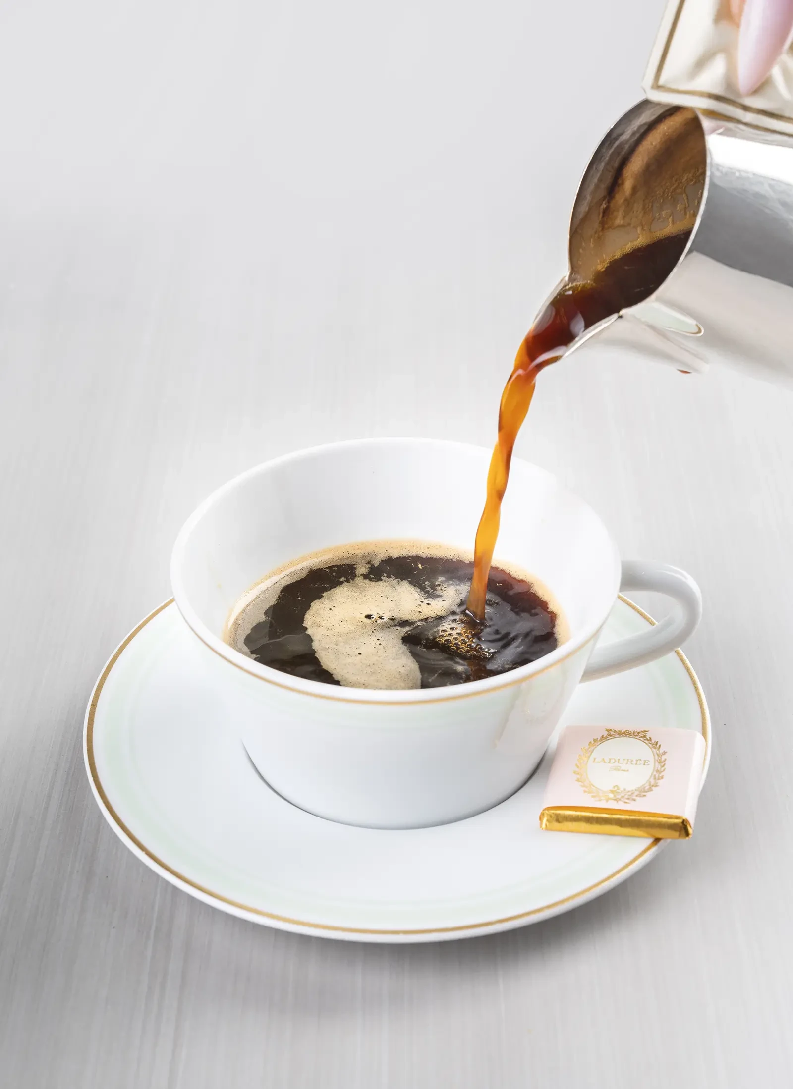 A cup of coffee with the Ladurée logo on it.