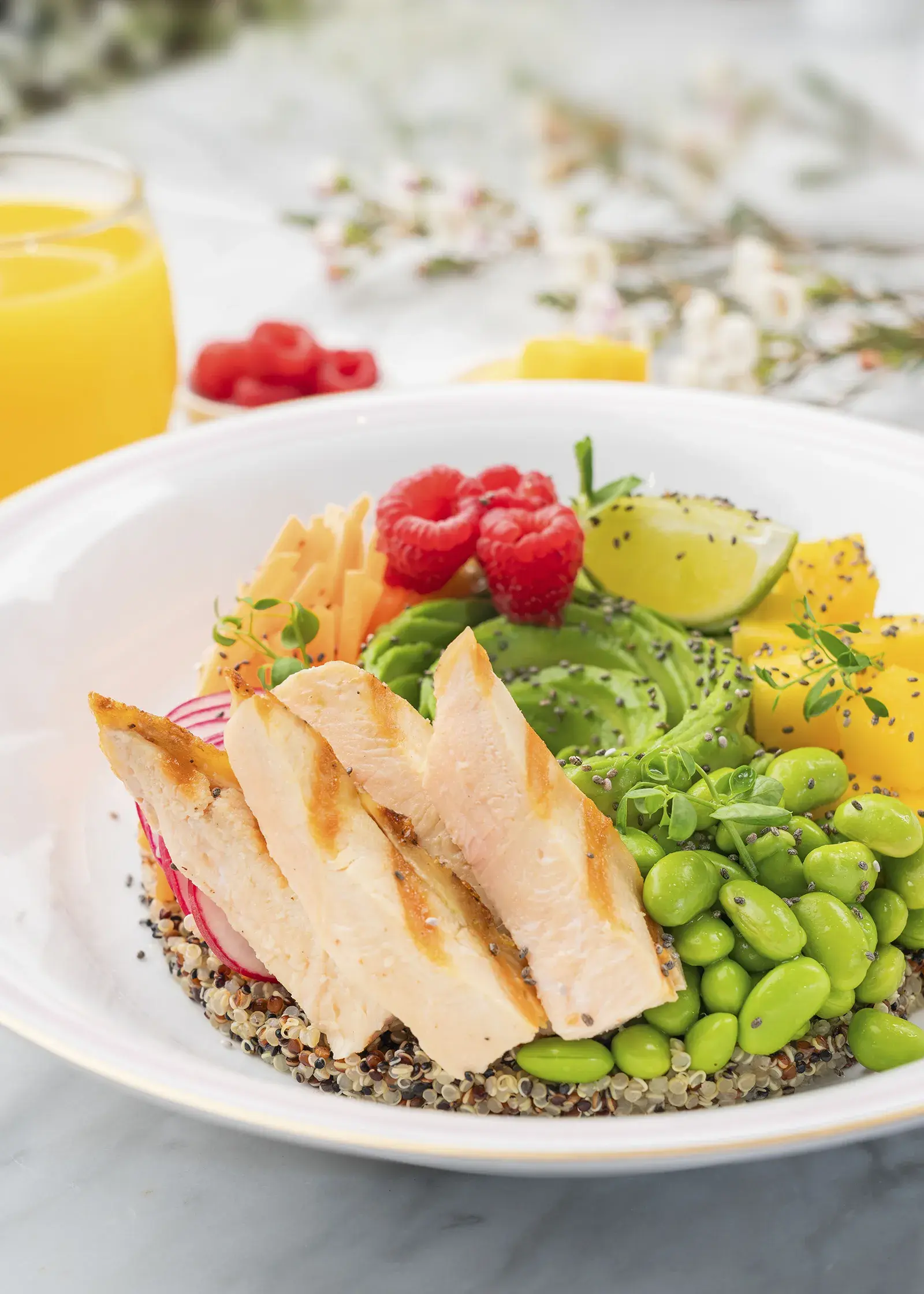 A poke bowl with chicken, quinoa, and fresh vegetables.