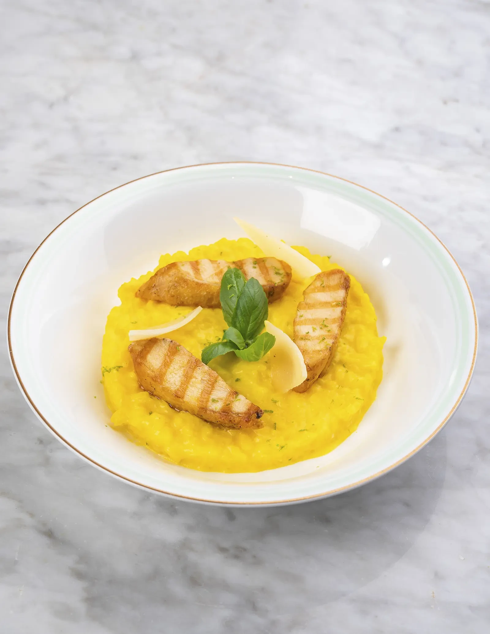 A bowl of golden saffron risotto with chicken pieces.