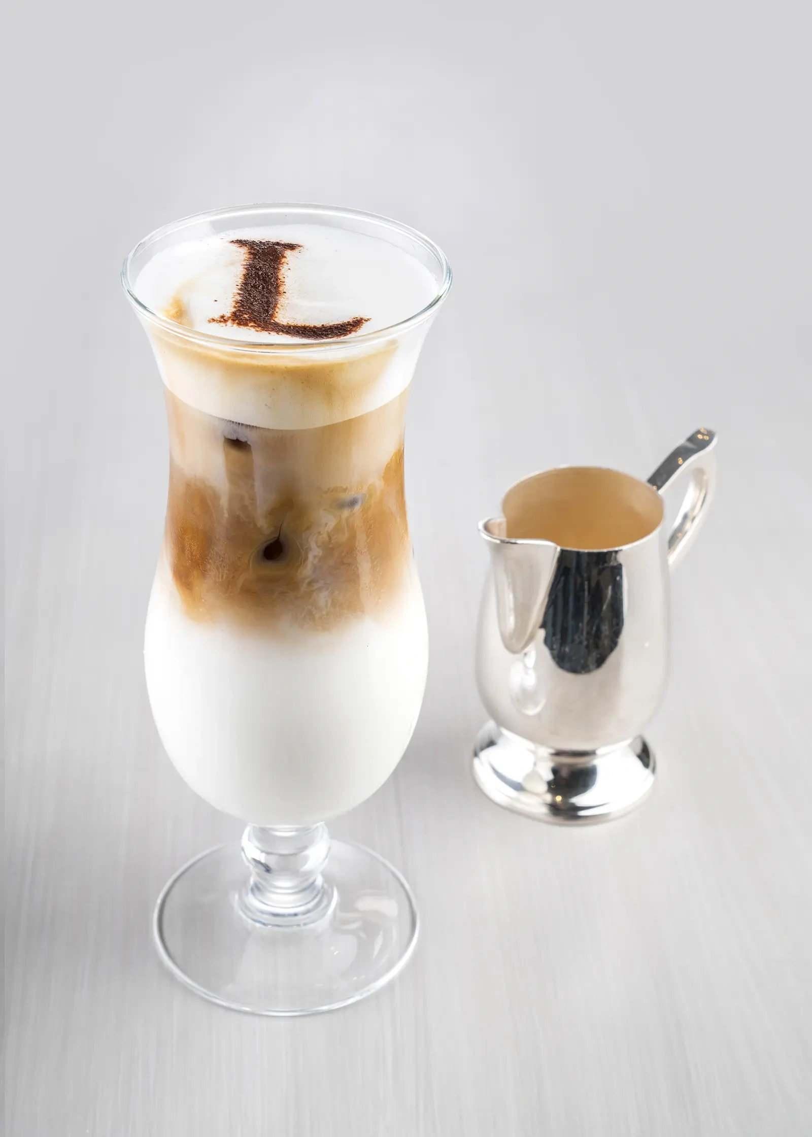 A glass of iced coffee with a layer of condensed milk.
