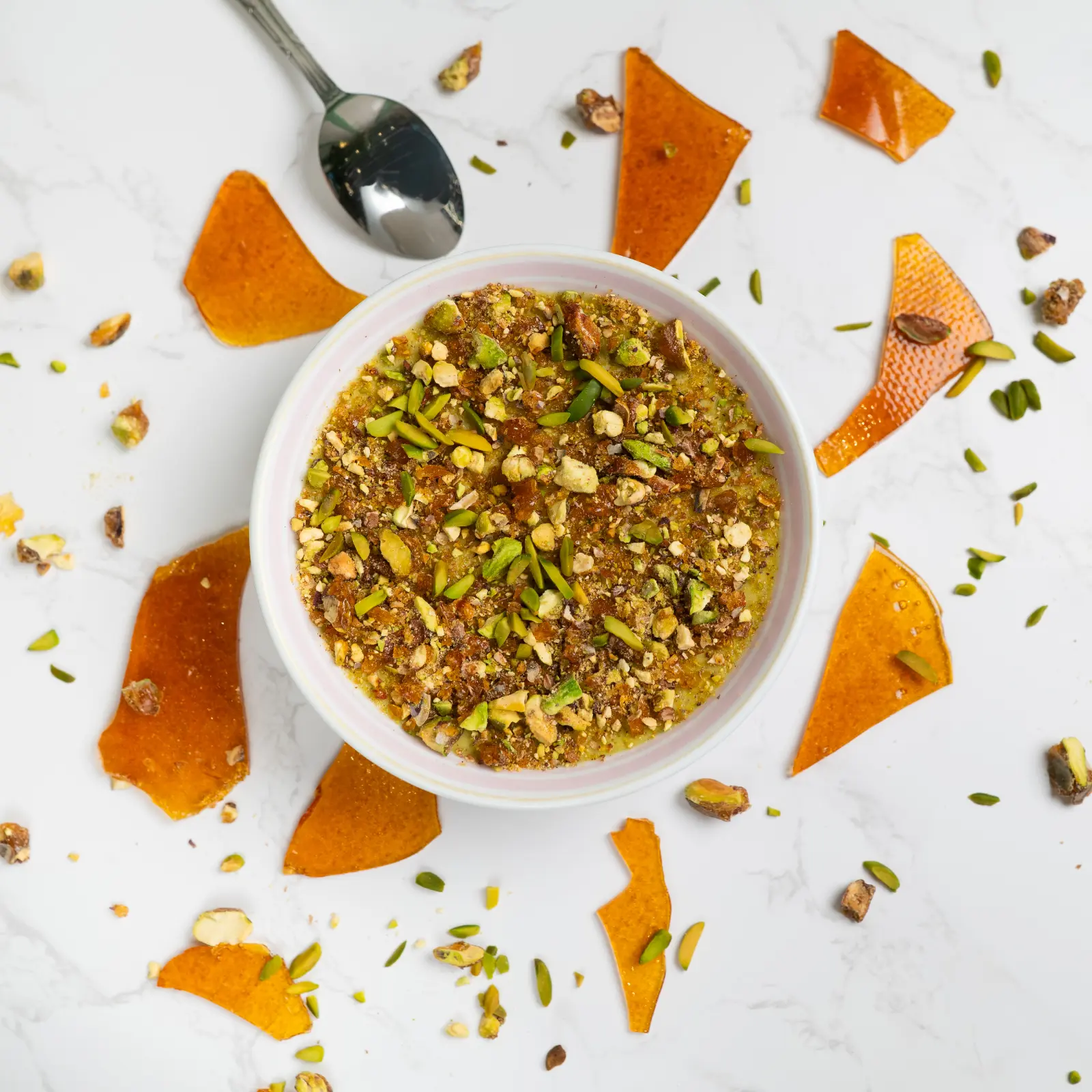 A ramekin of crème brûlée with a cracked caramelized top, garnished with pistachios.