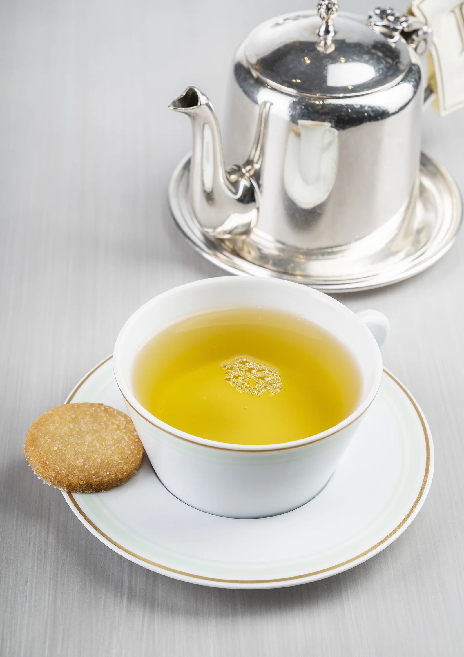 A cup with a warm yellow infusion garnished with a slice of lemon.