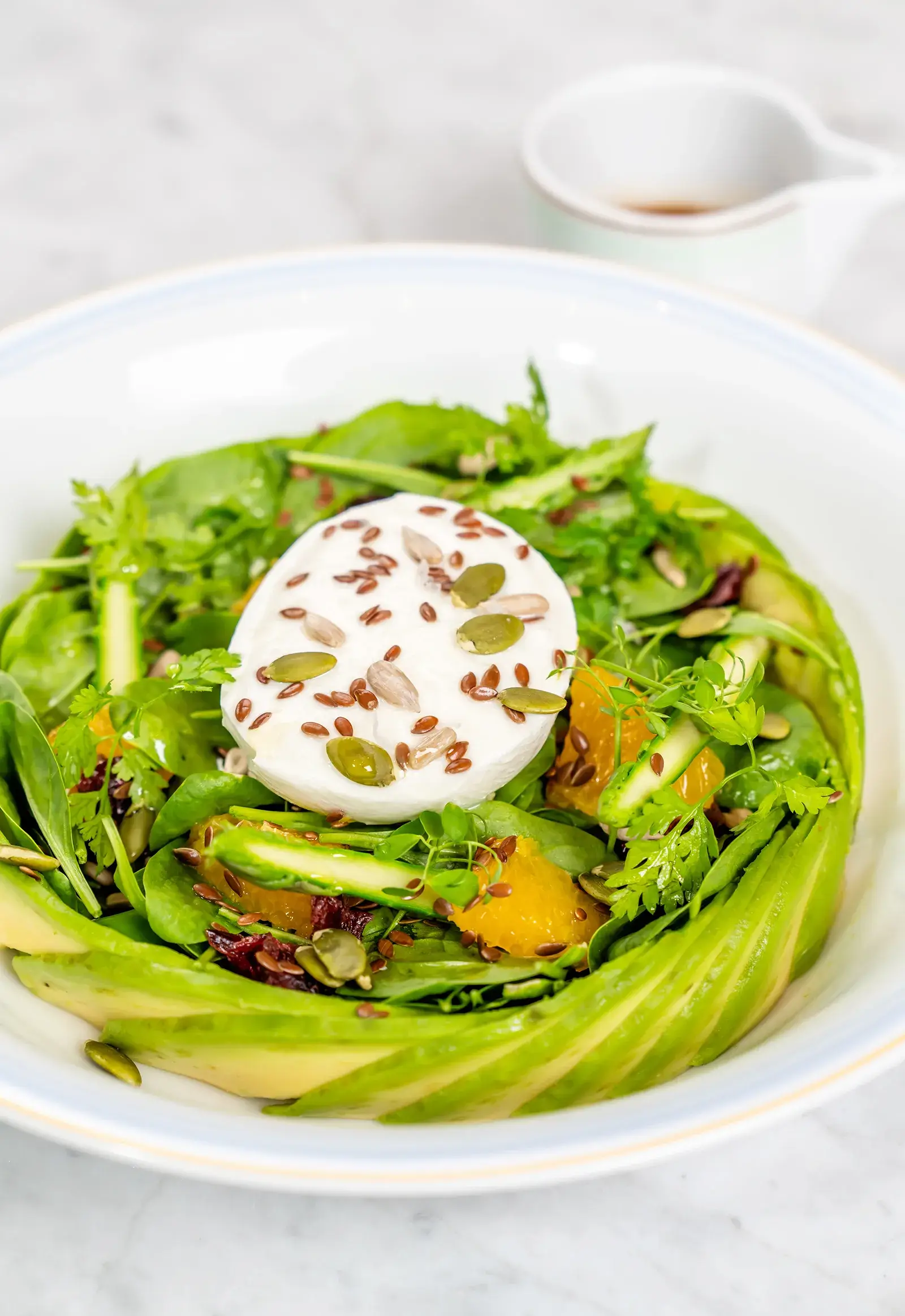 A fresh salad with baby spinach, avocado, and various toppings.