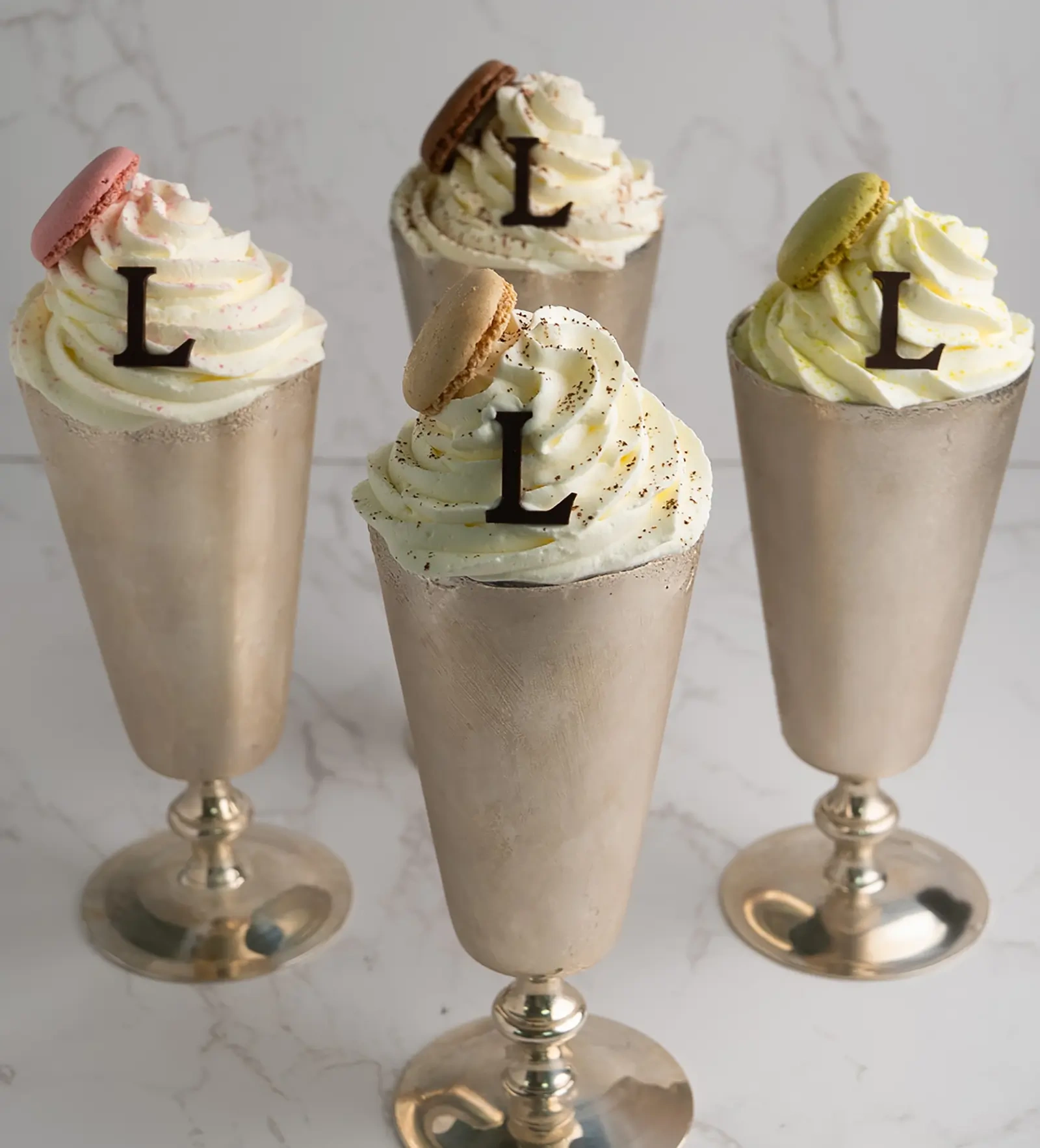 A pink milkshake topped with whipped cream and a macaron.