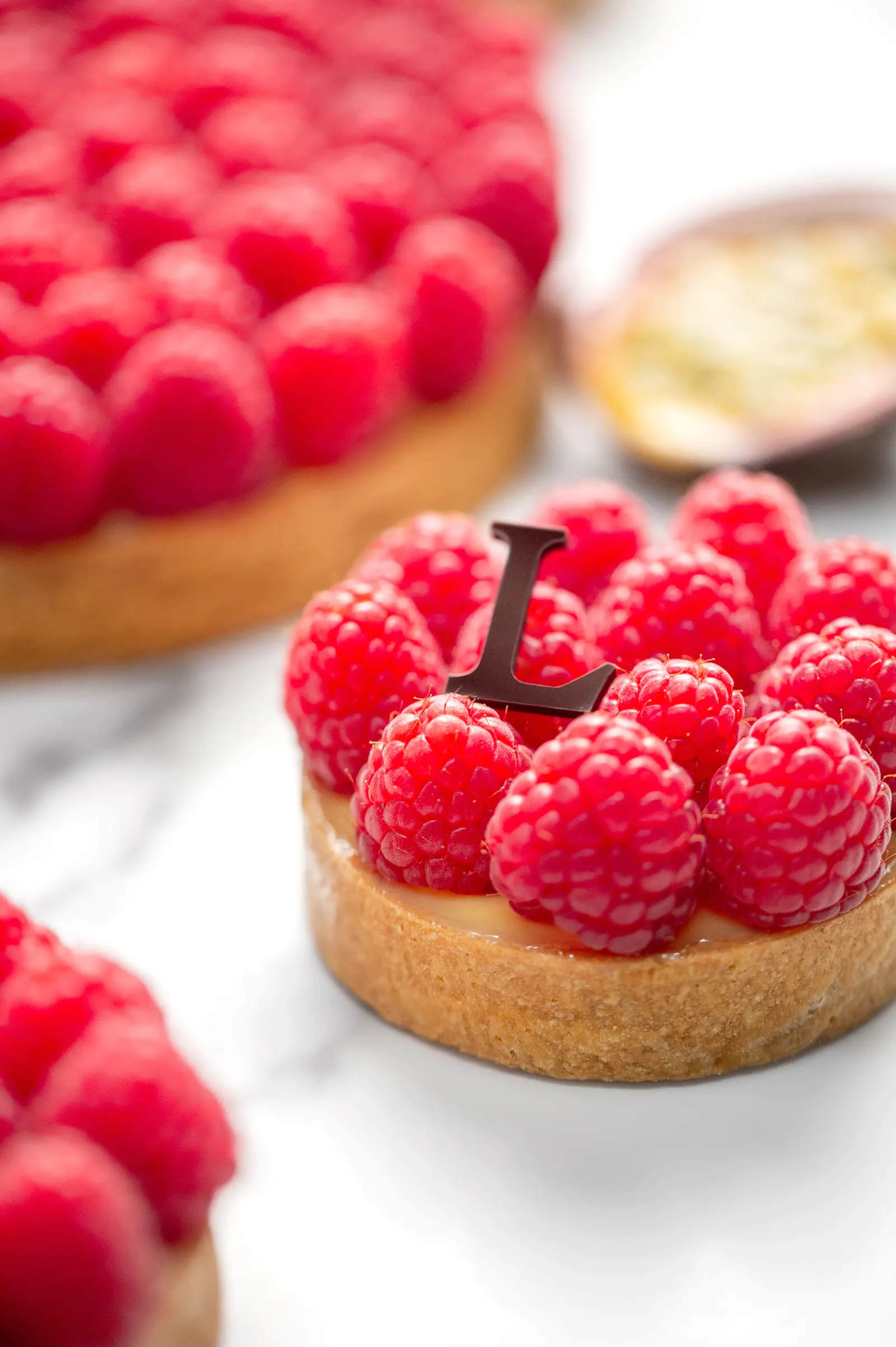 A vibrant tart filled with smooth passion fruit cream and fresh raspberries.