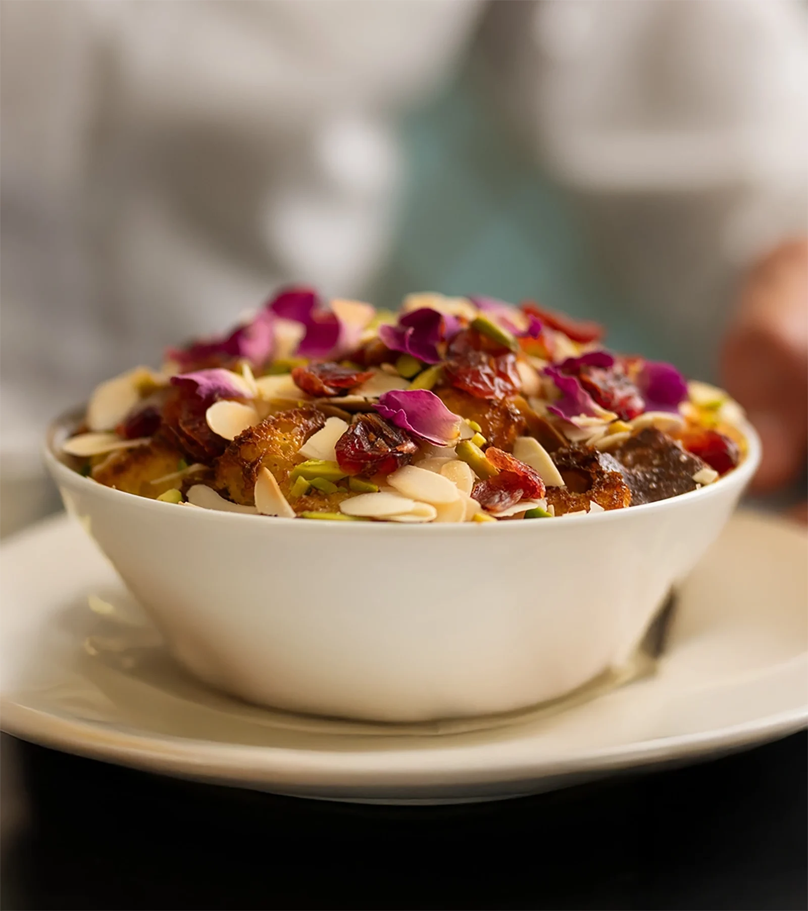 A bowl of bread pudding with nuts and berries.