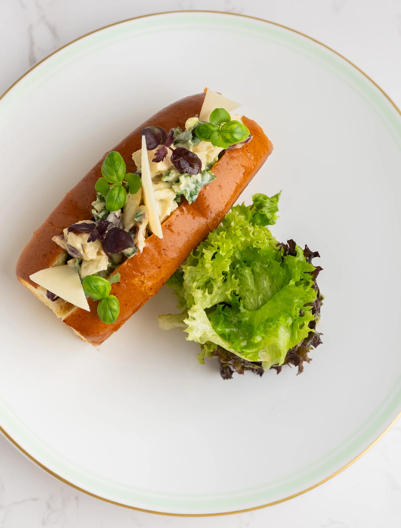 A bread roll filled with chicken, avocado, and Caesar dressing.