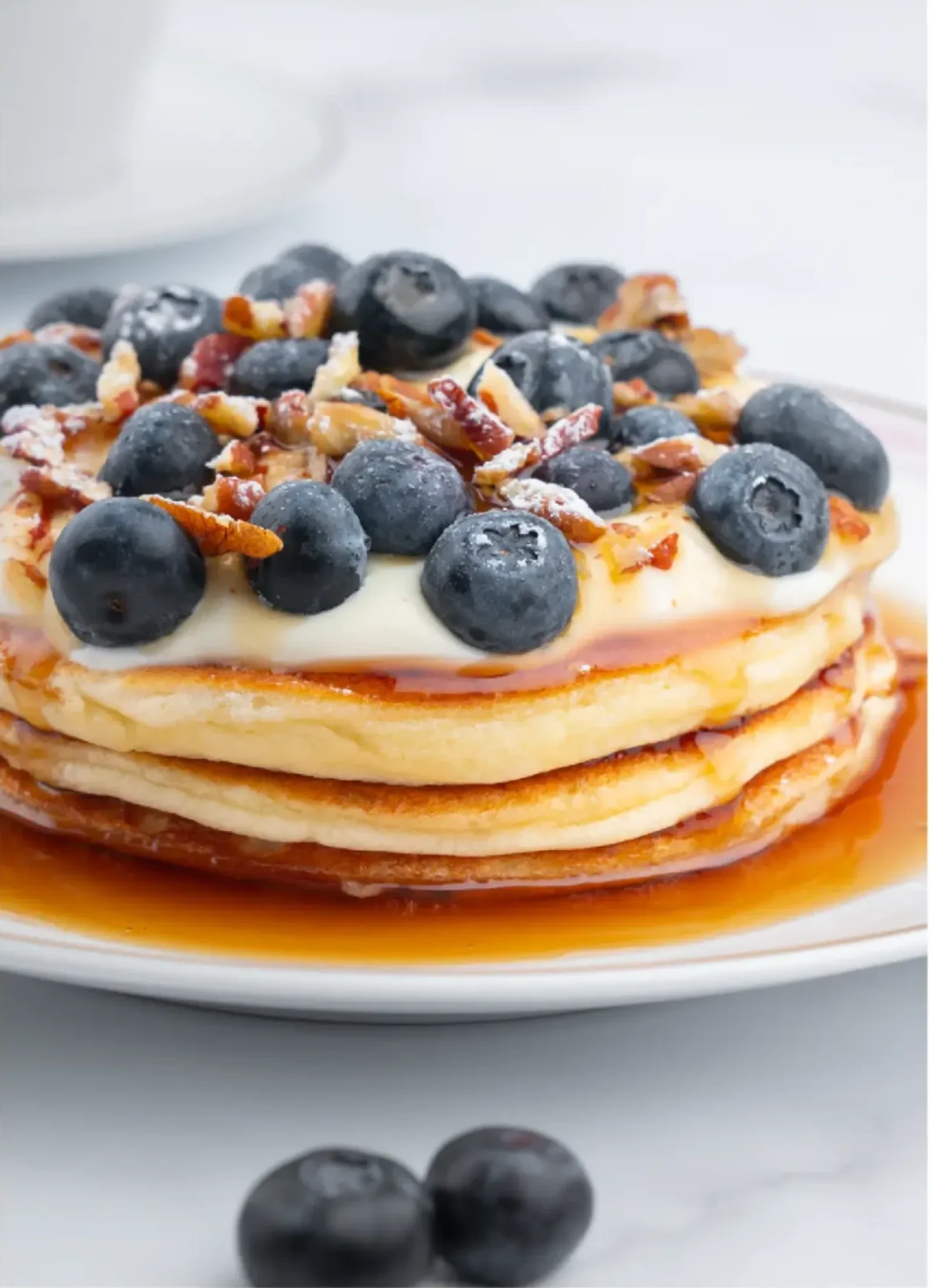A stack of pancakes topped with blueberries and cream.