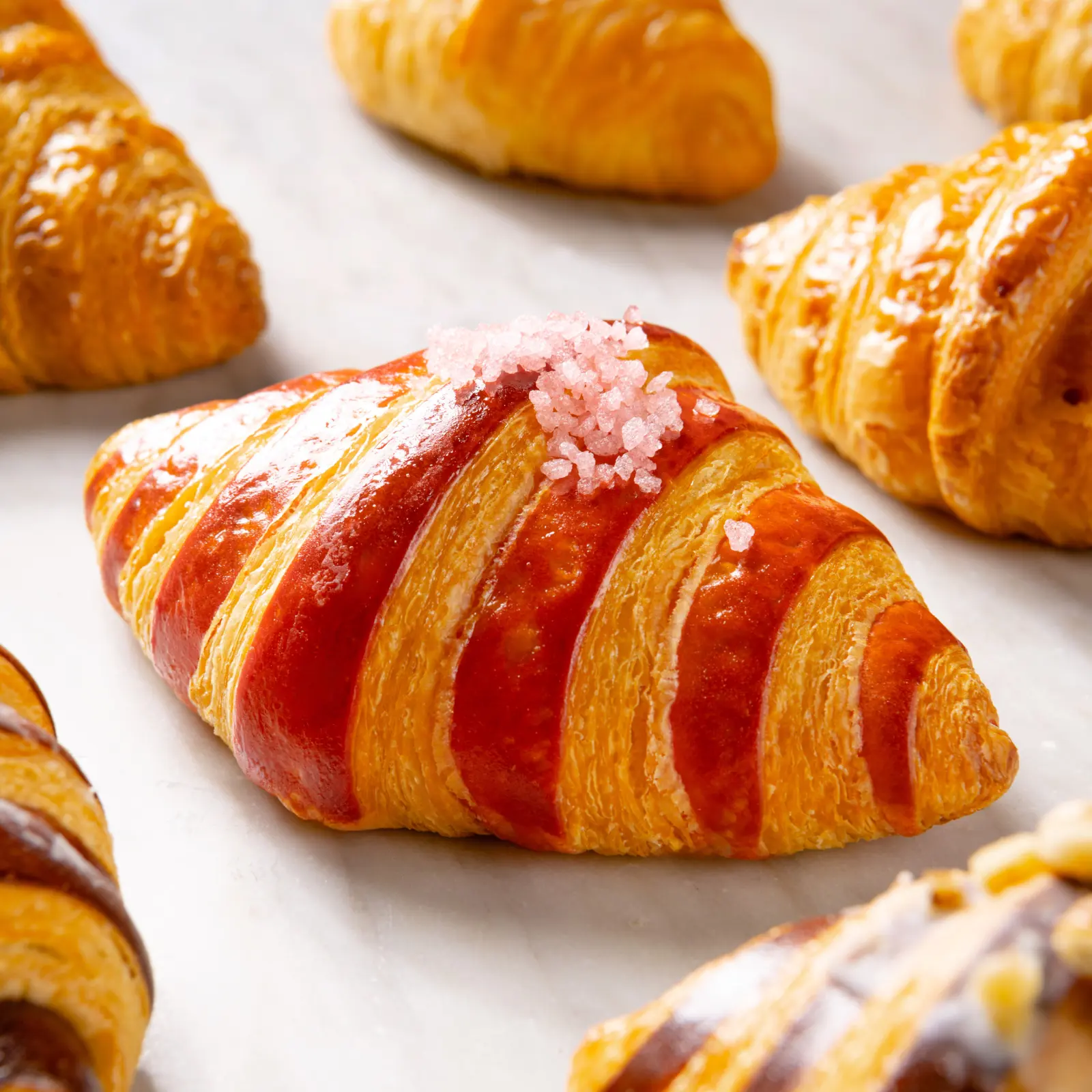 A small, pink croissant with a delicate rose flavor.
